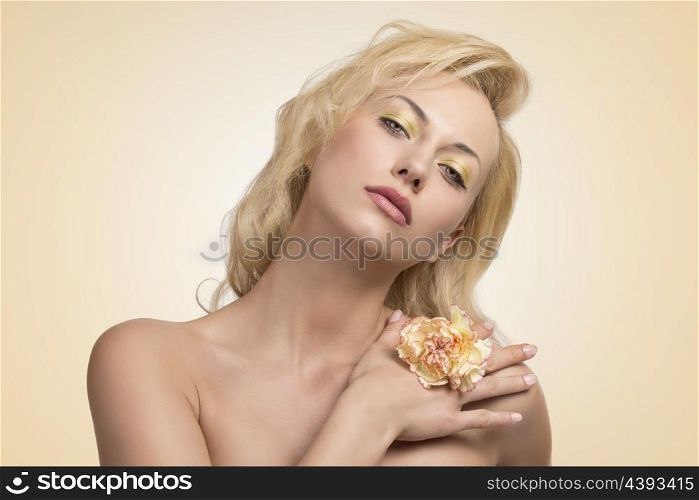 close-up portrait of pretty girl with colorful make-up, naked shoulders and long blonde hair posing with one flower in the hand