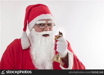 Close-up portrait of Santa Claus winking while eating chocolate bar over colored background