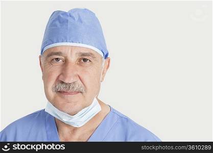 Close-up portrait of senior male surgeon over gray background