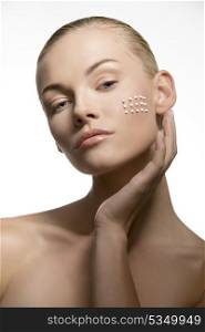close-up portrait of sensual blonde woman applying white cosmetics on her clear skin. Beauty treatment concept