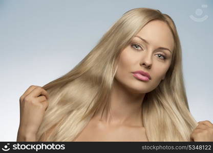 close-up portrait of sensual blonde woman with natural look and perfect skin showing her long smooth silky hair