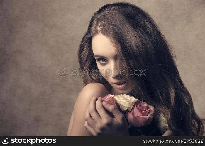 close-up portrait of sensual lady with long hair, taking bouquet of white and pink roses in the hands. Romantic expression and perfect skin, looking in camera