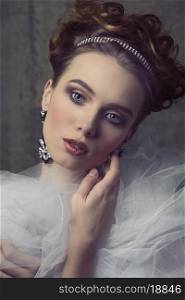close-up portrait of sensual woman with romantic retro style posing with shiny tiara in the elegant hair-style, precious earrings, vintage romantic dress with frill veil collar. Aristocratic vintage dame