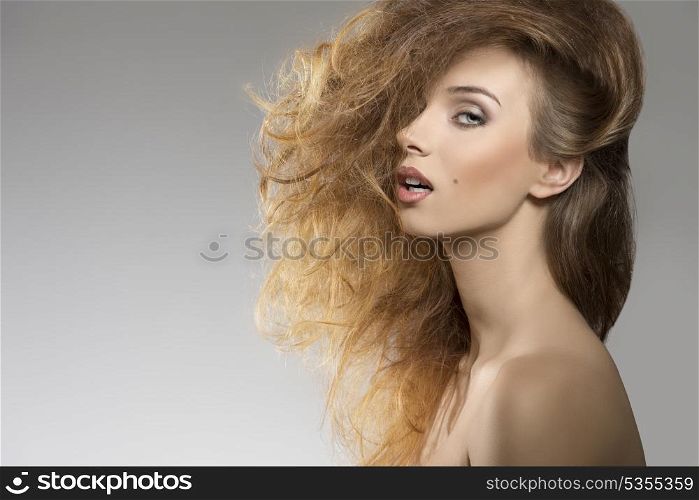close-up portrait of sexy girl with naked shoulders posing with bushy creative hair-style