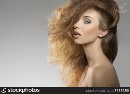 close-up portrait of sexy girl with naked shoulders posing with bushy creative hair-style