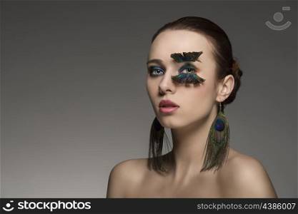 close-up portrait of sexy woman with brown hair and make-up and accessory inspired by peacock feathers