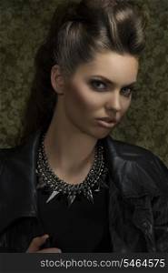 close-up portrait of sexy young brunette with gothic rock style, posing with brown modern hair-style, leather jacket and rock necklace. Looking in camera