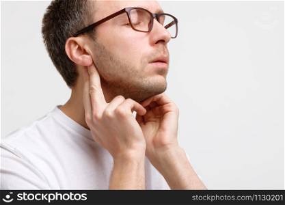 Close up portrait of sick man touches the lymph glands with his fingers near the ear, suffering from pain, closed eyes, isolated. Lymphadenitis, immunity weakened after illness, otitis.