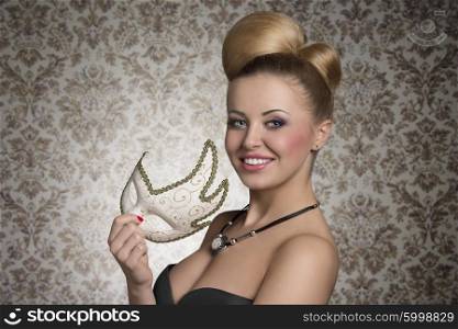 close-up portrait of smiling beautiful woman with creative elegant hair-style, cute make-up and stylish necklace taking cute decorated mask in the hand and looking in camera