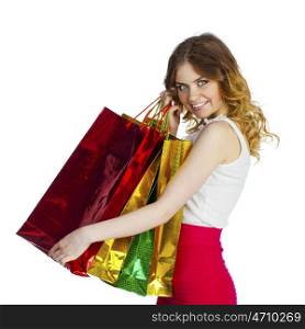 Close up portrait of smiling young blonde girl with colorful shopping bags in white dress posing on a white background