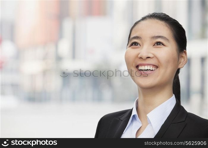 Close-up Portrait of smiling young businesswoman, looking up