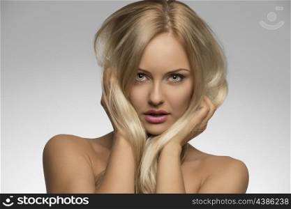 close-up portrait of splendid girl with natural style and pure skin posing with hands in silky smooth blonde hair