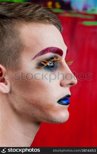 Close-up portrait of the handsome young man fashion model with make-up and big eyelashes