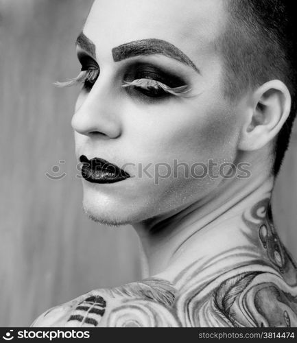 Close-up portrait of the handsome young man fashion model with make-up and big eyelashes