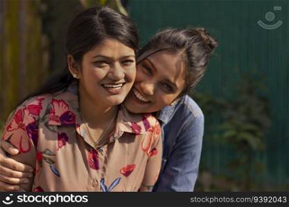 Close-up portrait of two smiling young women embracing each other