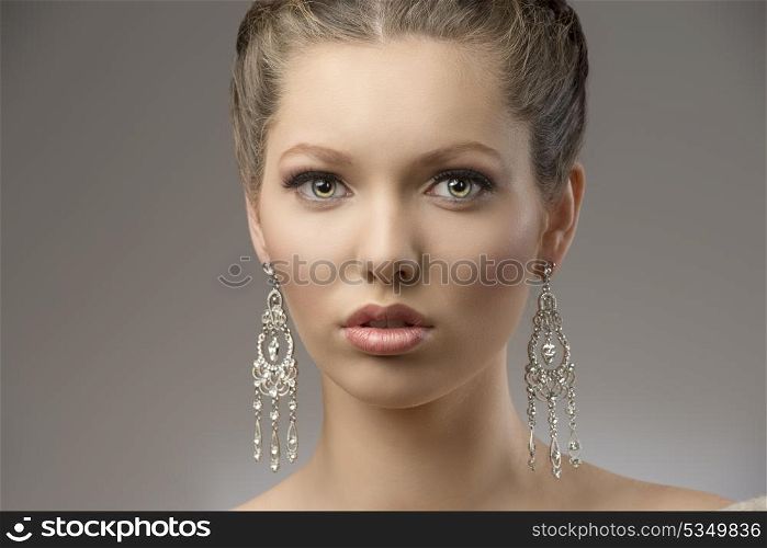 close-up portrait of very beautiful brunette girl with splendid eyes, creative hair-style and precious earrings. looking in camera