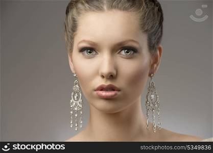 close-up portrait of very beautiful brunette girl with splendid eyes, creative hair-style and precious earrings. looking in camera
