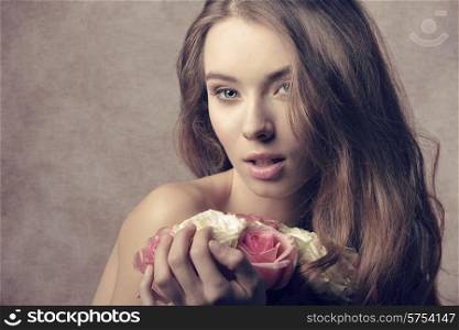close-up portrait of very pretty female with long hair, taking bouquet of white and pink roses in the hands. Sensual expression looking in camera