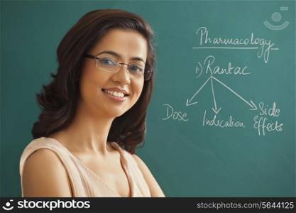 Close-up portrait of young female teacher against green board