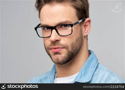 Close-up Portrait of young handsome caucasian man in jeans shirt over light background.. Close-up Portrait of young handsome caucasian man in jeans shirt over light background