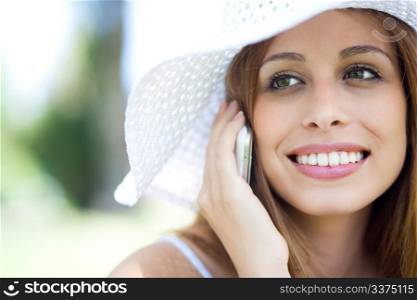 Close up portrait of young smiling woman in hat using mobile phone
