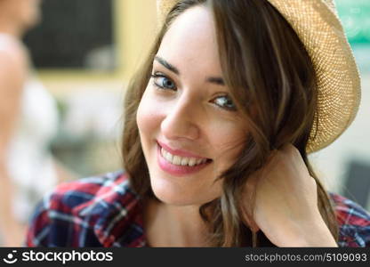 Close-up portrait of young woman with beautiful blue eyes wearing plaid shirt and sun hat