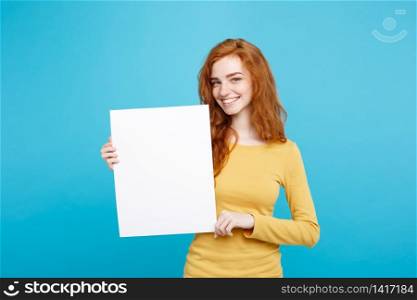 Close up Portrait young beautiful attractive ginger red hair girl smiling showing blank sign. Blue Pastel Background. Copy space.