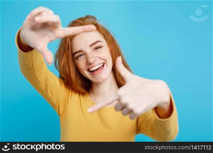 Close up Portrait young beautiful attractive redhair girl smiling looking at camera. Blue Pastel Background.. Close up Portrait young beautiful attractive redhair girl smiling making camera symbol. Blue Pastel Background.