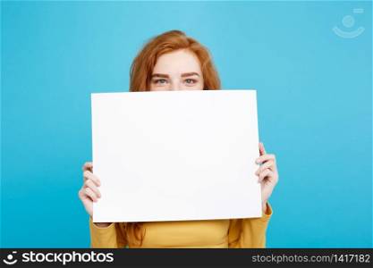 Close up Portrait young beautiful attractive redhair girl smiling showing blank sign. Blue Pastel Background. Copy space.