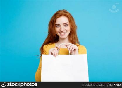 Close up Portrait young beautiful attractive redhair girl smiling with white shopping bag. Blue Pastel Background.