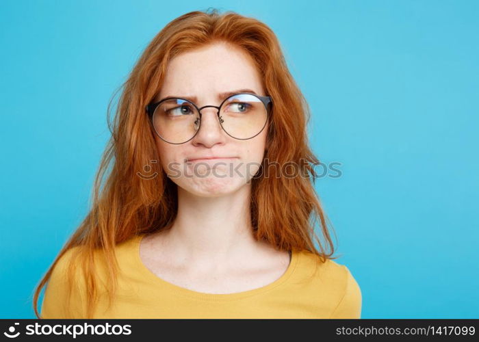 Close up Portrait young beautiful attractive redhair girl with eyeglass worry with something. Blue Pastel Background. Copy space.