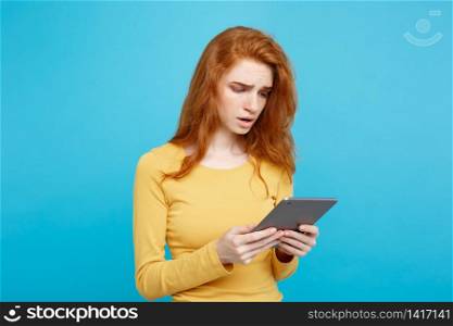 Close up Portrait young beautiful attractive tender ginger redhair girl happy smiling on digital table with wining something. Blue Pastel Background. Copy space.. People and Technology Concept - Close up Portrait young beautiful attractive tender ginger redhair girl shocking and sad on digital table with wining something. Blue Pastel Background. Copy space.