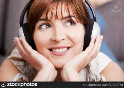 Close-up portrqit of a beautiful young woman listening music with headphones