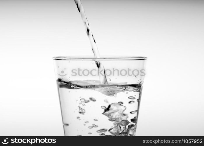 Close up pouring drinking water into glass, studio shot