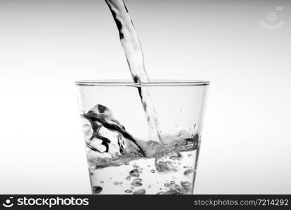 Close up pouring drinking water into glass, studio shot