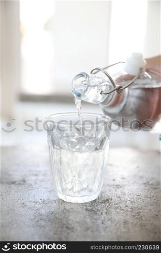 Close up pouring water to glass from the bottle on table in coffee shop