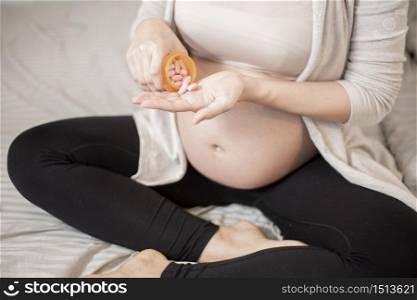 Close up pregnant woman eating vitamin pills