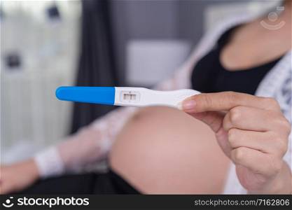 close up pregnant woman holding pregnancy test