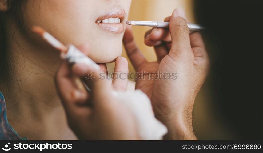 Close-up, Profesional stylist putting on lipstick on the lip of the bride during getting ready for the wedding celebration