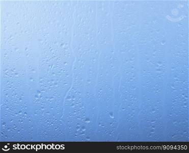 Close up raindrops and water runs on glass window pane surface over grey and blue sky background on rainy day