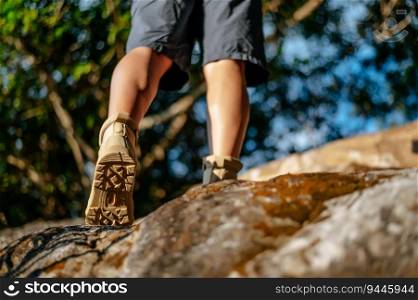 Close up, rear view trekking shoes of Hiker walking on the rock  in the forest Trail with sunlight, copy space