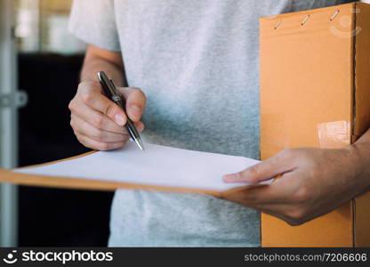 Close up recipient of the product is using the pen signing to receipt document at front of the house.