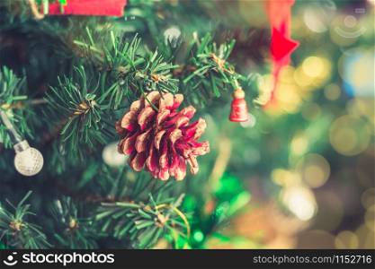 Close-up red pine cone decorated on Christmas tree with blurred and bokeh background. Xmas and New Year theme.