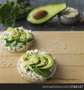 close up rice cake with avocado slices wooden chopping board