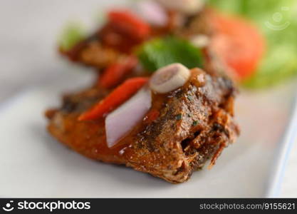 Close up Selective focus appetizers with spicy sardine mixed with herb in white ceramic tray, copy space