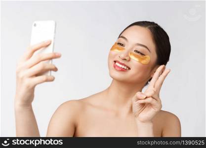 Close up selfie of beautiful happy woman with eye mask on face.Woman with eyes mask taking selfie with mobile phone at home enjoying relaxation.. Close up selfie of beautiful happy woman with eye mask on face.Woman with eyes mask taking selfie with mobile phone at home enjoying relaxation and