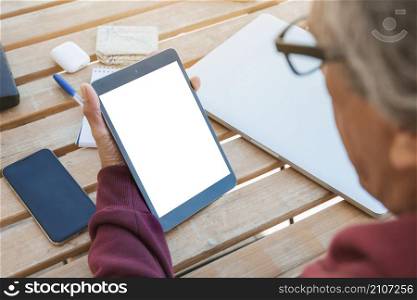 close up senior man looking digital tablet with blank white screen wooden table