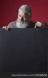 close up senior man with grey beard pointing her finger blank black placard