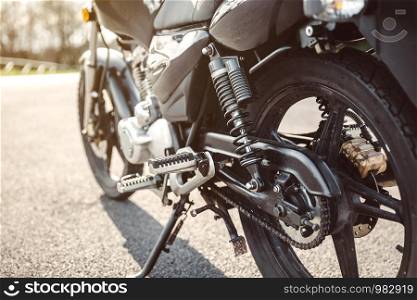 Close up shock absorber, chain and disk brake of black shiny motorcycle . Shock absorber and chain of black motorcycle