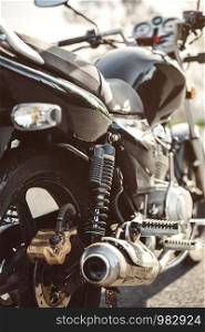 Close up shock absorber, exhaust pipe and disk brake of black shiny motorcycle . Shock absorber and exhaust pipe of black motorcycle